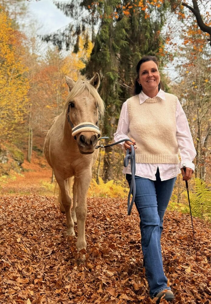 Wiebke spaziert mit einem Pferd durch herbstlichen Wald